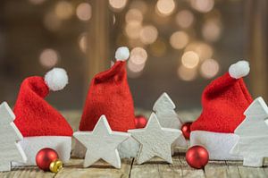 Bonnets de Père Noël avec décoration de Noël sur une table en bois sur Alex Winter