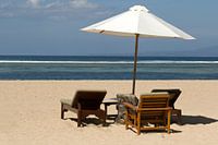 Parasol met ligstoelen op het strand van Sanur op Bali