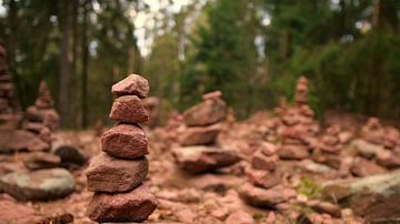 Türmchen aus gestapelten Steinen in sanfter brauner Farbe im Wald. von Timon Schneider