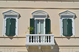 Symmetrische Gebäudefassade mit Balkon, Fenstern und grünen fensterläden von Tomherkules