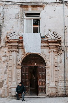 Italie | Pouilles | Bari | homme devant une porte pastel sur Iris van Tricht