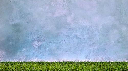 Groen gras tegen een blauwe betonnen achtergrond