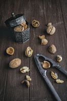 Walnuts lie in a metal tin and on a dark brown tray