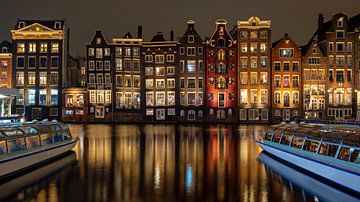 Middeleeuwse huizen en rondvaart boten op het  Damrak in Amsterdam Nederland bij nacht van Eye on You