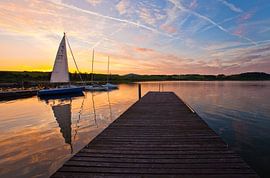 A sailing boat is reflected in Lake Wallersee