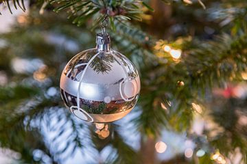 Zilverkleurige kerstbal in de kerstboom. van Wim Stolwerk