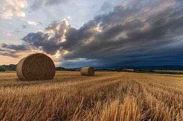 Heuballen auf dem Feld mit dramatischen Wolken von Christina Bauer Photos