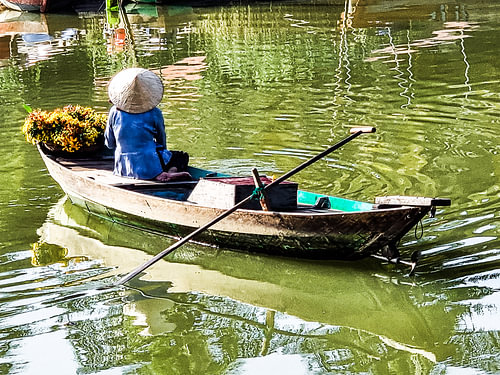 Une vendeuse de fleurs vietnamienne au bord du fleuve