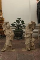 Stenen beelden van Aziatische vrouwen en mannen bij Wat Pho Buddha tempel.