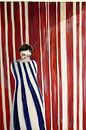Red striped wall with woman in blue dress by Franka Poulain thumbnail