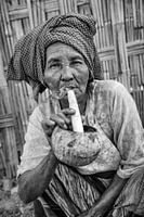 Old woman smokes traditional cheroot cigar in front of her home in Baghan in Myanmar