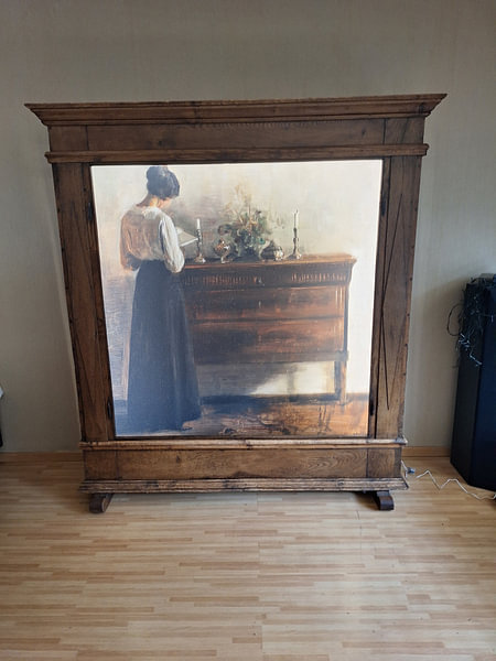 Customer photo: Interior with the artist's wife standing at a chest of drawers reading, Carl Holsøe, on ArtFrame