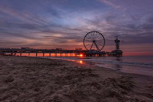 Strand van Scheveningen, pier en het reuzenrad bij zonsondergang met zonnestralen door de pier