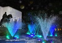 blauwe waterfontein geeft show aan rijder met zwarte paard