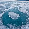 Een stuk doorzichtig ijs op een cirkel van doorzichtig blauw ijs op het ijs van het baikalmeer, berg van Michael Semenov