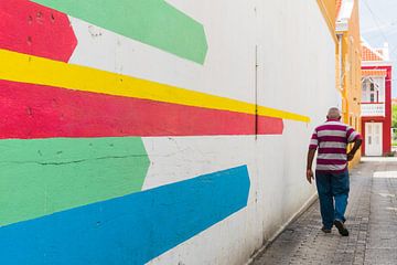 Man met gestreept shirt en kleurrijke muurschildering, Otrobanda, Curacao van Paul van Putten