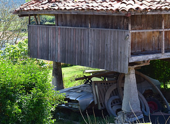 Traditioneller Getreidespeicher in Nordspanien mit einem Autowrack darunter