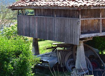 Traditionele graanschuur in noord-Spanje met een autowrak eronder van Studio LE-gals