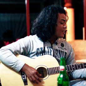 Indonesische jongen speelt gitaar I van André van Bel