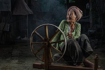 Oude balinese vrouw met haar spinnewiel in een klein dorpje bij Ubud, in Bali. van Anges van der Logt