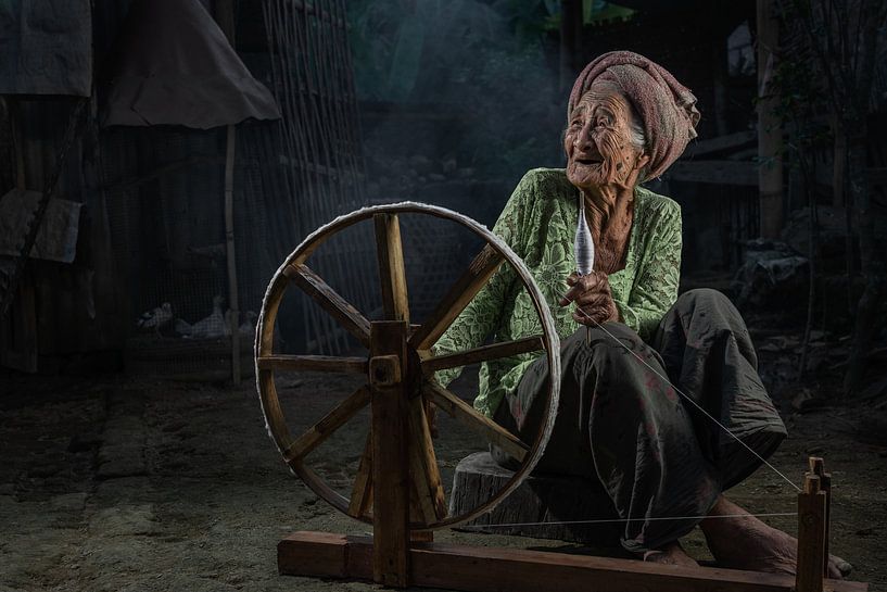 Alte balinesische Frau mit ihrem Spinnrad in einem kleinen Dorf in der Nähe von Ubud, Bali. von Anges van der Logt