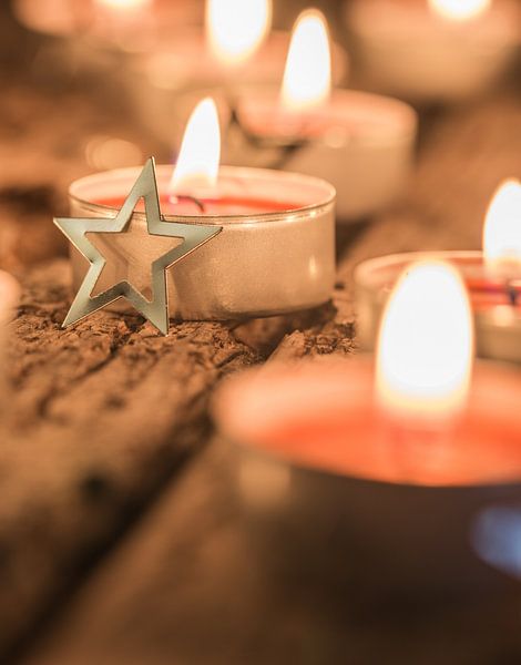 Festlich brennende rote Advents- und Weihnachtskerzen mit sternförmigen Ornamenten von Alex Winter