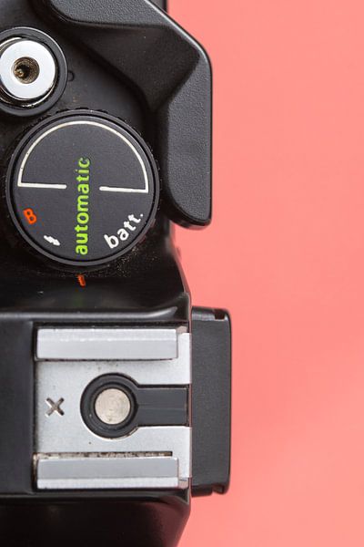 Nahaufnahme einer alten 'Praktica'-Kamera auf hellrosa/orangem Hintergrund von Iris Koopmans