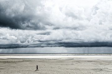 groot strand met grijze wolken, eenzame man van Alexander Baumann