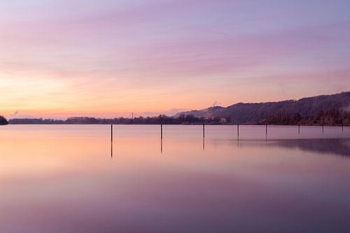 mistige zonsopkomst over het water met reflectecerende palen en pastel