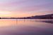 nebliger Sonnenaufgang über dem Wasser mit reflektierenden Pfählen und Pastellfarben von Kim Willems