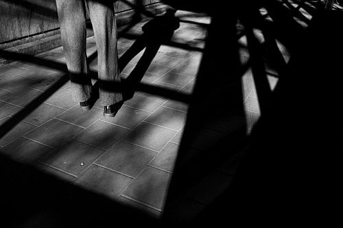 Jeu d'ombres en ville - Photo de rue minimaliste en noir et blanc représentant une femme dans l'encadrement d'une fenêtre