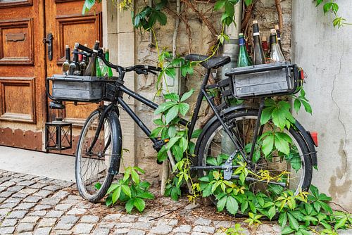Een zwarte fiets leunt tegen een muur van een huis.