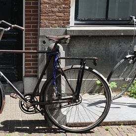 Herenfiets tegen paal aan gracht in Delft sur Mariska van Vondelen