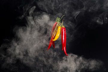 Hete pepers met rook tegen zwarte achtergrond van Wim Stolwerk
