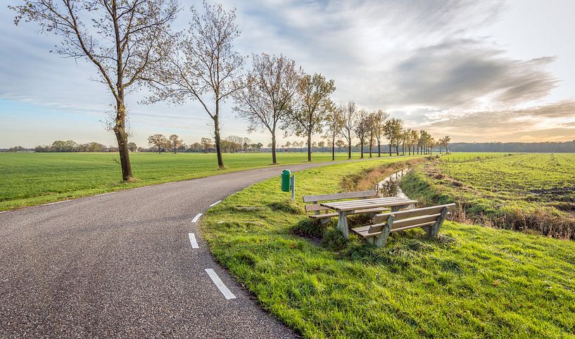 Kromme landweg met houten picknickset in de berm van Ruud Morijn