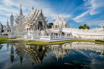 The white Wat Rong Khun temple in Chiang Rai, Thailand with a reflection in the water. by Twan Bankers