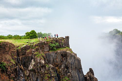 Toeristen aan de rand van de Victoria watervallen