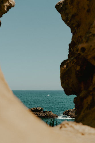 Blick durch die Felsen auf ein Segelboot, das auf dem Atlantischen Ozean segelt