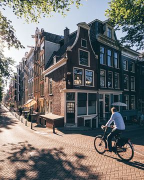Fietser op straathoek langs de Amsterdamse grachten met typisch Amsterdamse huisjes van Michiel Dros