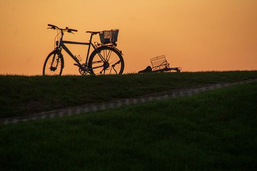 Fiets op dijk tegen ondergaande zon