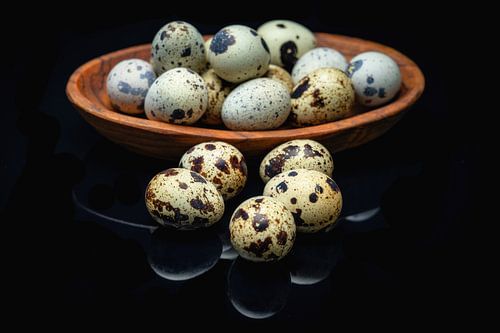 Kwarteleitjes in olijfhouten schaaltje op spiegelplaat