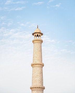 White marble tower of the Taj Mahal against the bright blue sky. van butfirstsalt