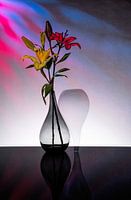 two tapered vases with a yellow and red lily inside.