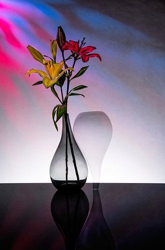 zwei spitz zulaufende Vasen mit einer gelben und roten Lilie im Inneren.