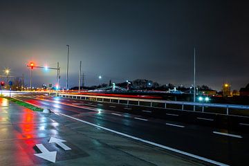 Brug met drukke straat en verkeerslichten 's nachts