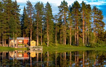 naaldbos en houten recreatiewoning reflecteren in Zweeds meer van Jan Fritz