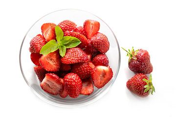 Dessert van verse aardbeien met pepermuntgarnituur in een glazen schaal, geïsoleerd met schaduwen op van Maren Winter