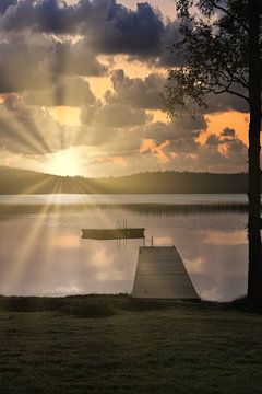 A wooden jetty on the lake in the morning mist, flooded with sunlight and a calm reflection. by Martin Köbsch