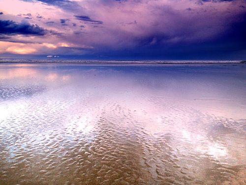 Paarse wolken reflecteren op het strand