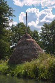 Traditioneller Heuhaufen mit Holzstange in ländlicher Sommerlandschaft